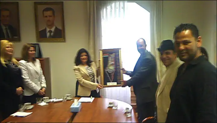 نضال حمدان رئيس جمعية اصدقاء اليرموك يقدم هدية رمزية للسيدة عبير الجرف – القائم بالاعمال للسفارة السورية